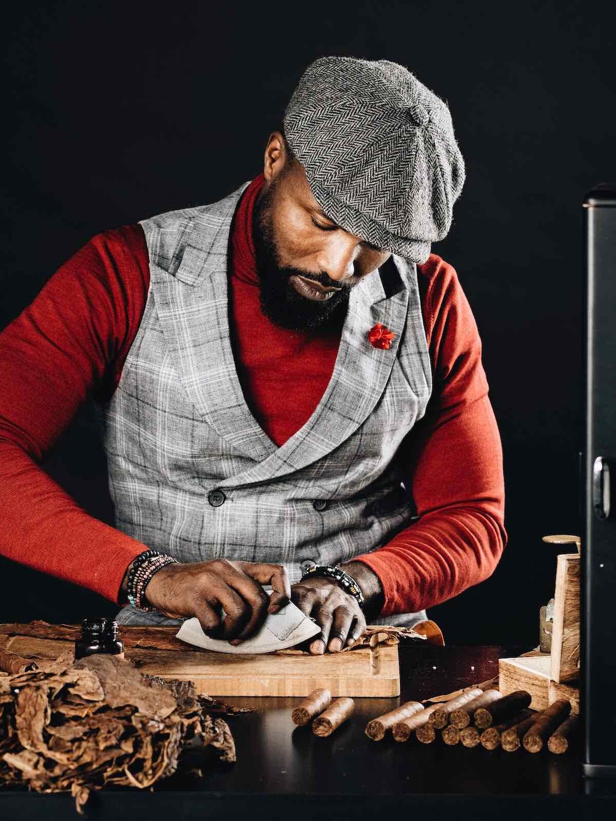 Zigarrendreher rollt Zigarren neben Humidor